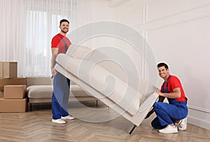 Professional movers carrying sofa in new house