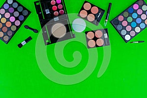 Professional multi colored eyeshadow makeup palette and brushes on green background copy space for your text