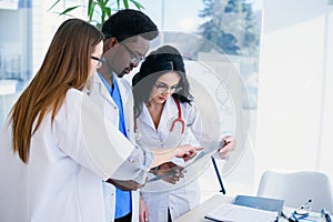 Professional multi ethnic doctors are examining a patient`s X-ray. Two female doctors and one male doctor work together