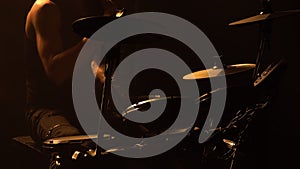 Professional musician playing drums and percussion cymbals in a dark smoky studio with yellow lights. Close up of the