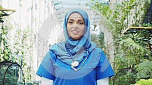 Professional Muslim medical doctor works in front of hospital office. Portrait of young and attractive Middle Eastern