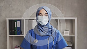 Professional Muslim medical doctor works in hospital office. Young and attractive Middle Eastern female physician in