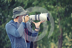 Professional nature and wildlife photographer outdoor hand holding camera with big pro lens taking pictures