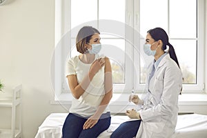 Professional nurse talking to a young woman who`s about to get an antiviral vaccine