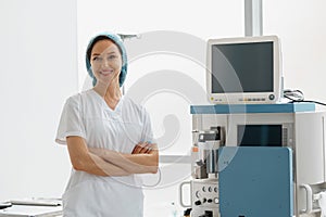 Professional nurse in uniform standing in operating room on background of medical equipment