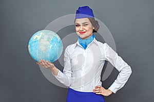 Professional Occupation. Stewardess standing isolated on grey showing globe looking camera confident