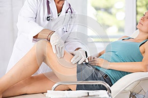 Professional orthopedic traumatologist examining injured knee of female patient