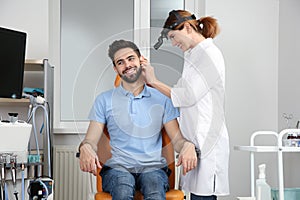 Professional otolaryngologist examining man in clinic