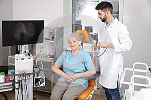 Professional otolaryngologist examining senior woman with endoscope in clinic
