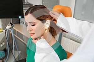 Professional otolaryngologist examining woman in clinic