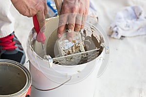 Professional Painter Loading Paint Onto Brush From Bucket