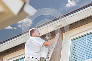 Professional Painter Using Small Roller to Paint House Fascia