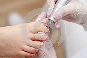 Professional pedicure procedure removing old nail polish with device in beauty spa salon