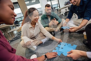 Professional people playing puzzle on the floor of the office.Team Building