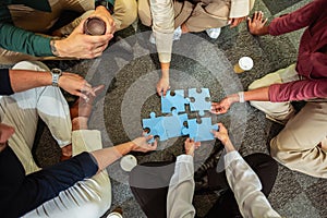 Professional people playing puzzle on the floor of the office.Team Building