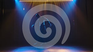Professional performance of breakdancing, hip hop performed by a stylish male street dancer. Silhouette of a man in a