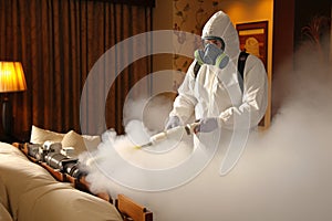 Professional pest control technician in a mask and protective suit fumigating with toxic gas
