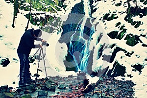 Professional photograph takes with camera on tripod photo of winter waterfall.