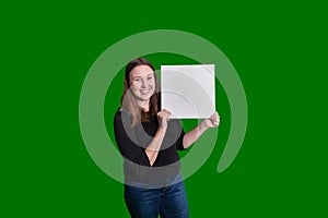 Youthful lady holding up empty blank sign on her side smiling captured portrait on green screen