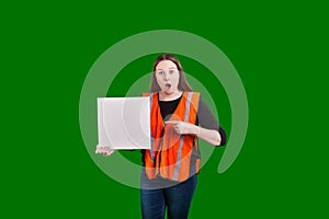 Female worker wearing safety orange vest pointing a finger at blank white board