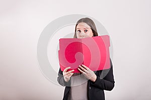 Women in business suit holding red file peeking over folder