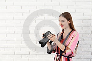 Professional photographer with  camera near white brick wall. Space for text