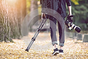 Professional photographer with camera and tripod in autumn.