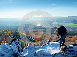 Professional photographer takes photos with mirror camera and tripod on snowy peak