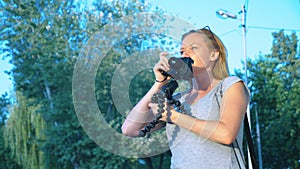 A professional photographer, takes pictures in an amusement park, a woman presses a button of a gadget among a flowering