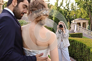 Professional photographer taking photo of wedding couple outdoors