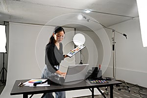Professional photographer woman using laptop at table in her lighting studio