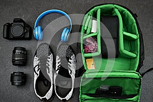 Professional Photography Gear : camera and lenses, blue wireless headphone and black shoes on grunge gray background .