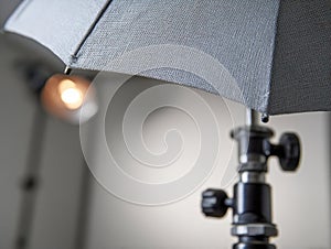 Professional photography studio lighting setup featuring an open textured umbrella diffuser and adjustable light stand with a