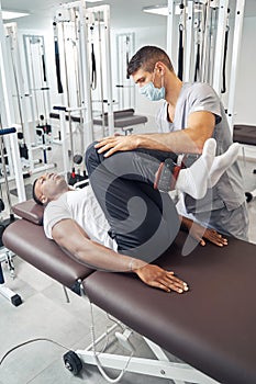 Professional physical therapist rehabilitating male patient legs