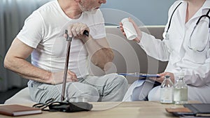 Professional physician prescribing medicine to senior man sitting on couch