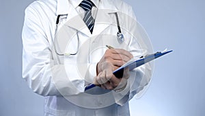 Professional physician writing in paper documents, keeping medical records