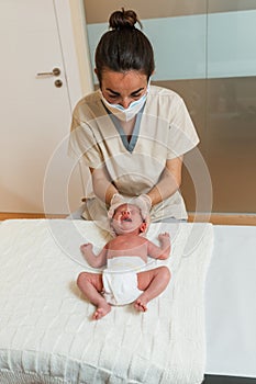 Professional physiotherapist doing a positional plagiocephaly correction on a newborn baby.