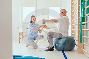 Professional physiotherapist exercising with an injured patient using a blue ball