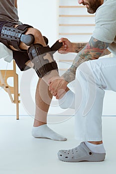 Professional physiotherapist helps the patient to put on an orthosis for the first time