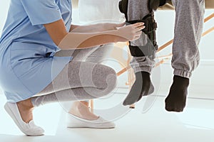 Professional physiotherapist helps the patient to put on an orthosis for the first time