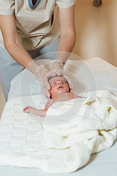 Professional physiotherapist performing a cranial base assessment in a newborn baby.