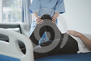 A professional physiotherapist is stretching the patient's legs, the patient has muscle dysfunction due to hard work.