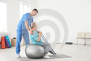 Professional physiotherapist working with elderly patient in rehabilitation center photo