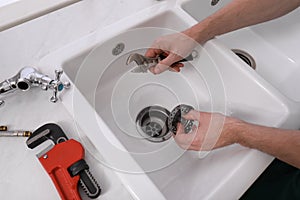 Professional plumber fixing water tap in kitchen, above view