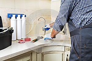 Professional plumber fixing water tap for water purification filter.