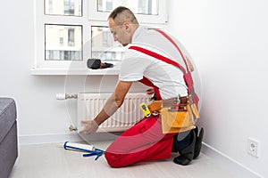 Professional plumber installing new heating radiator in room