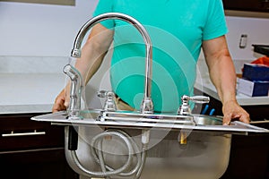 Professional plumber master sets the sink in the kitchen