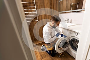 Professional plumber with plunger and instruments near sink.