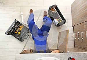 Professional plumber with set of tools working indoors