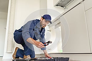 Professional plumber taking adjustable wrench from tool bag for repairing pipes